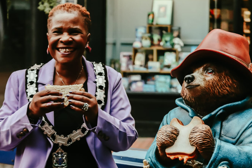 Deputy Major of Reading sitting with a statue of Paddington Bear